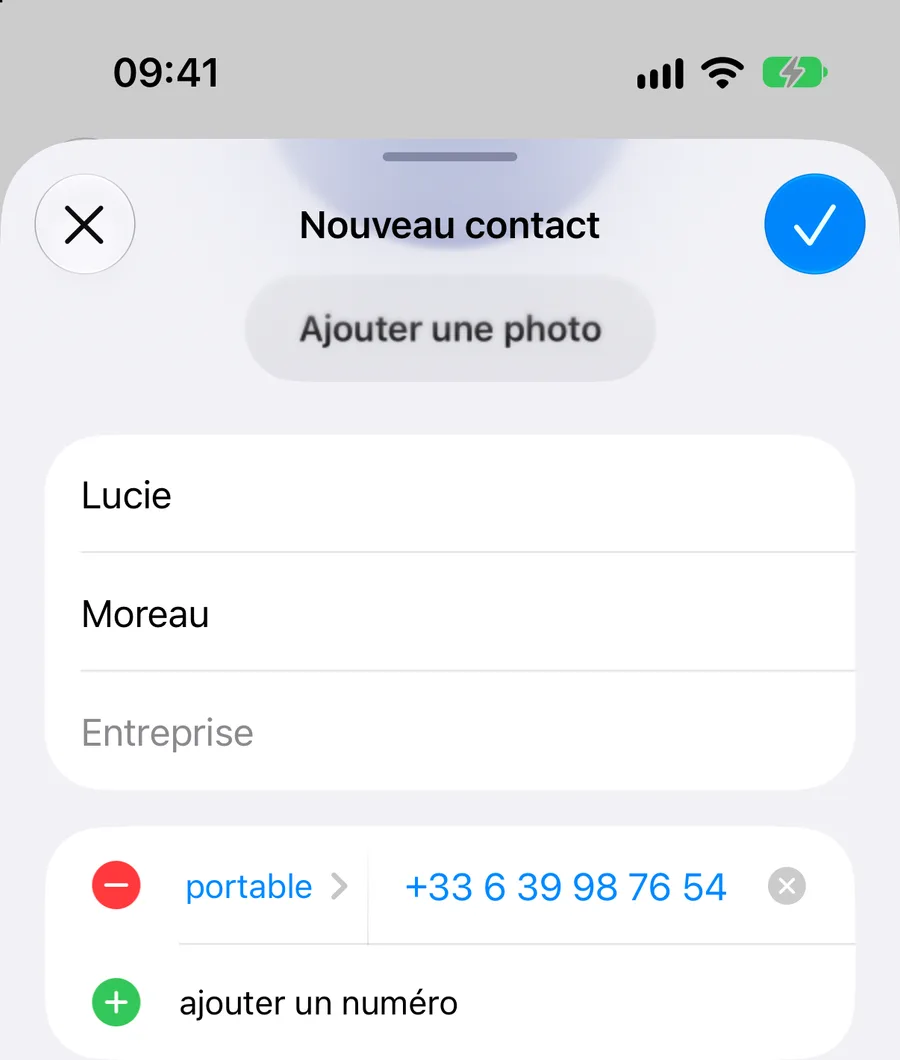 Fiche Nouveau contact en cours de saisie, avec un bouton Ajouter une photo en haut. Prénom : Lucie. Nom : Moreau. Le champ Entreprise est vide. En dessous, un numéro de portable saisi au format international, +33 6 39 98 76 54, puis la ligne ajouter un numéro.